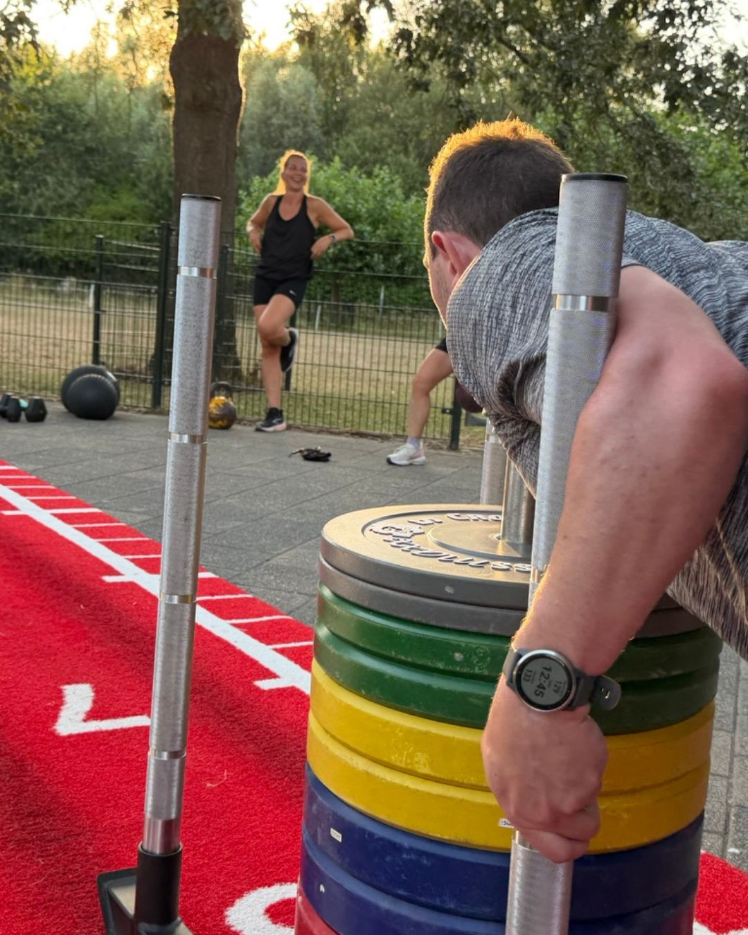 Sled push op de voorgrond, teamgenoot geniet op de achtergrond